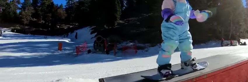snowboard enfant : jeune enfant débutant le snowboard sur une pente douce