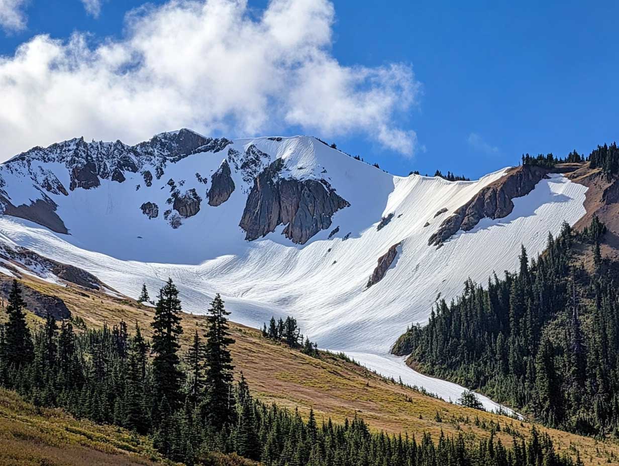 sécurité en montagne : paysage de montagne enneigée avec un skieur équipé pour la sécurité