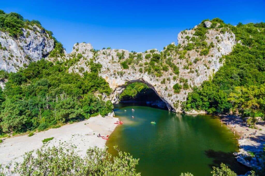 descente en canoë : canoë naviguant sur la rivière des gorges de l'Ardèche avec des falaises en arrière-plan